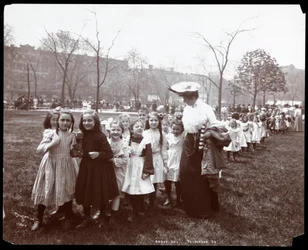 Bambini in una lunga fila guidati da una donna nel Tompkins Square Park, New York, 1904